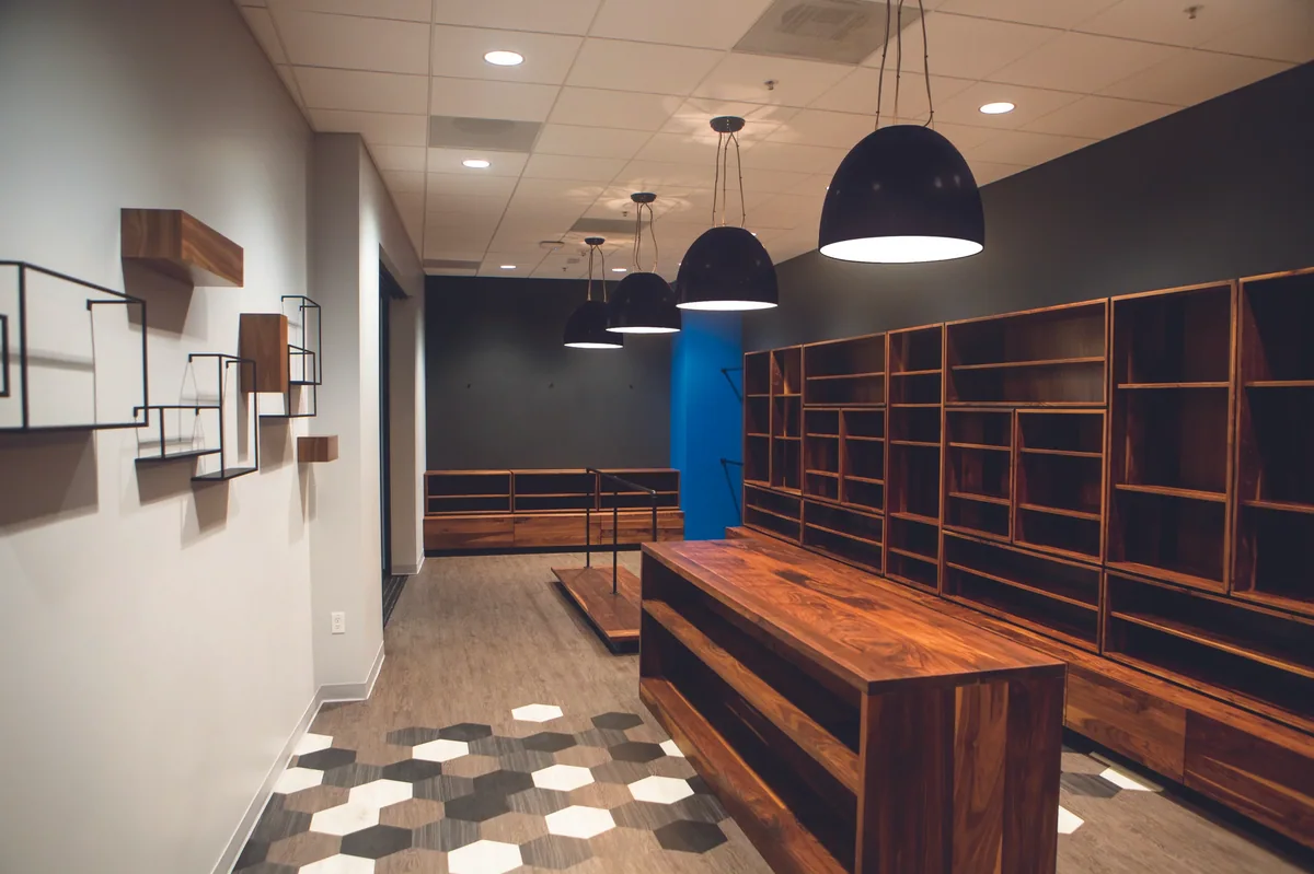 Store interior with floating logo shelves, walnut millwork and a hexagon tile floor